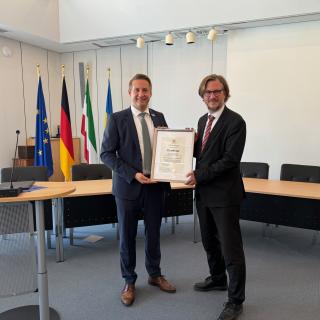 Regierungspräsident Thomas Schürmann überreicht Bürgermeister Dominik Pichler die Urkunde, die die Stadt als Ort mit Heilquellenkurbetrieb auszeichnet.